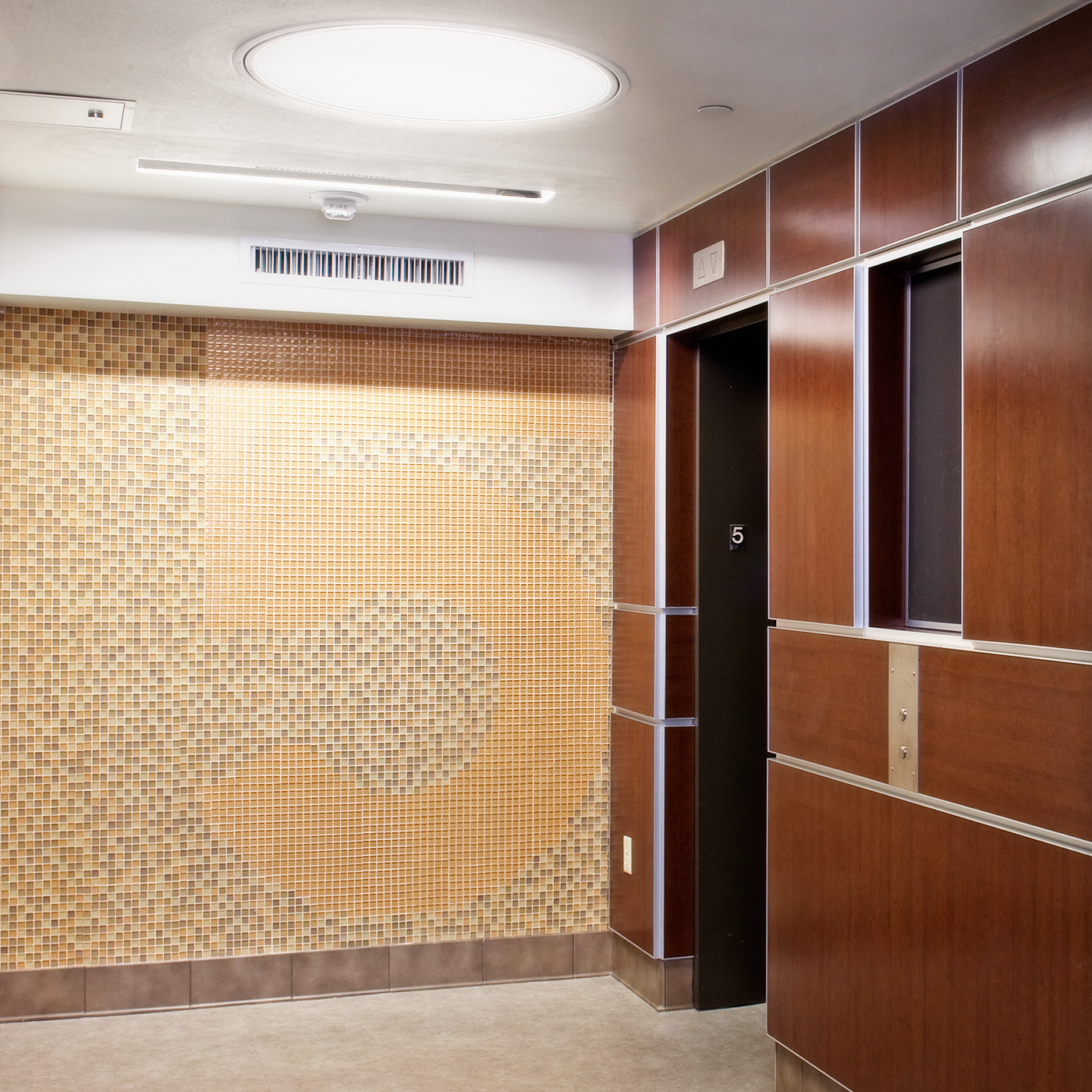 An elevator lobby with the number 5 written out in tile on the wall.