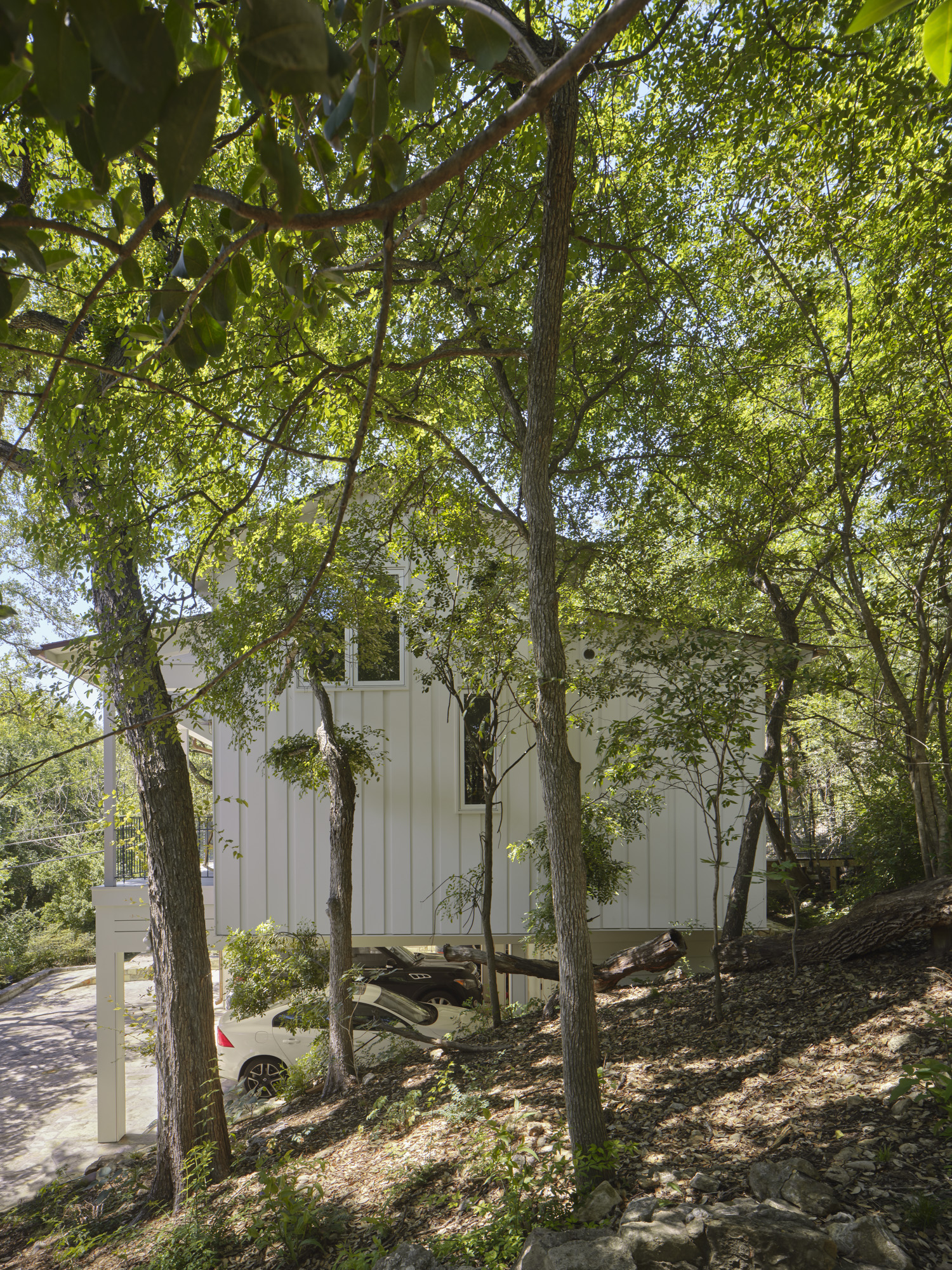 Side profile view of a small white house build into a will surrounded by trees.