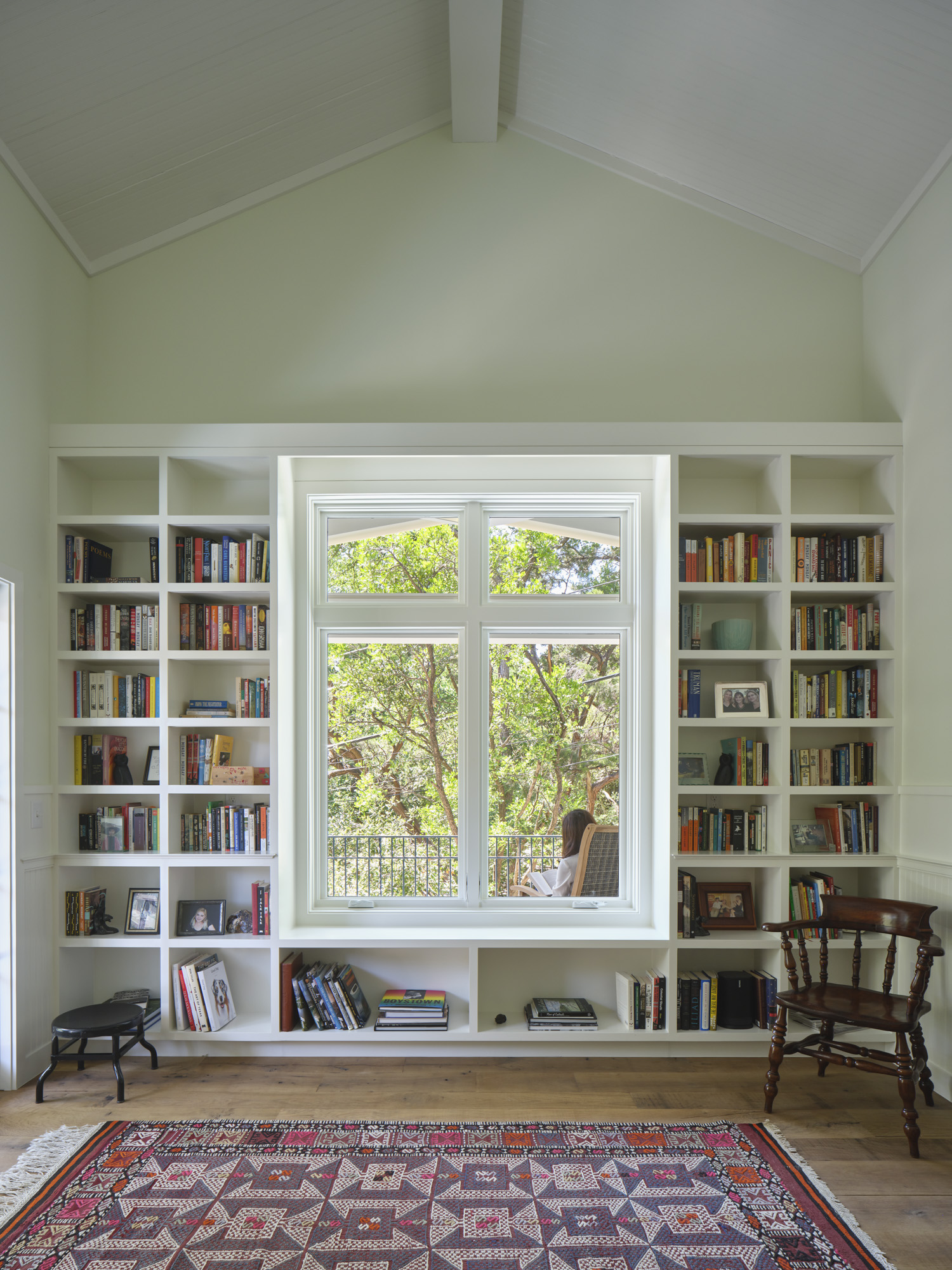 Bookshelf's surrounding the central window of a white room.